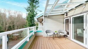 A wooden deck with two wicker chairs and a small table, overlooking a forested area. - Gibsons Garden Hotel (Gibsons)