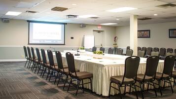 A conference room with a long table, chairs, a projector screen, and a whiteboard.