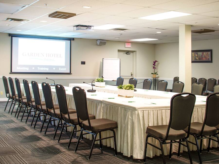 A conference room with a long table, chairs, a projector screen, and a whiteboard.