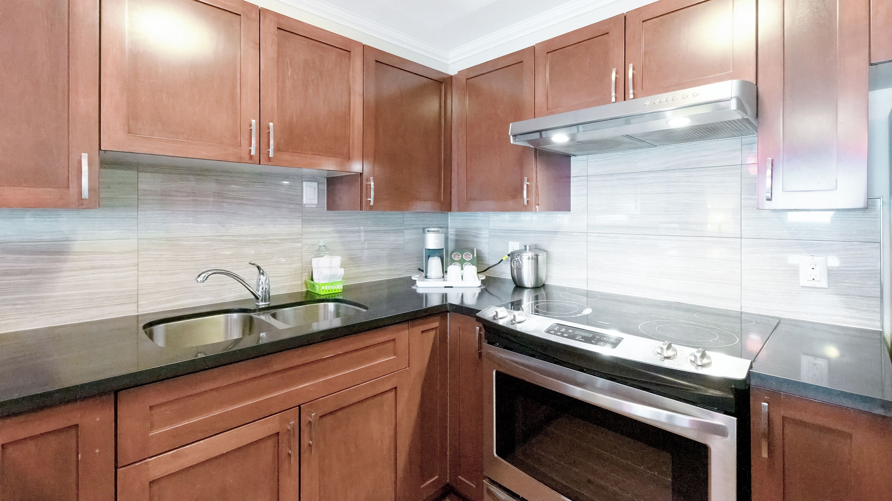 A modern kitchen with wooden cabinets, stainless steel appliances, and a black countertop.