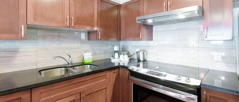 A modern kitchen with wooden cabinets, stainless steel appliances, and a black countertop.