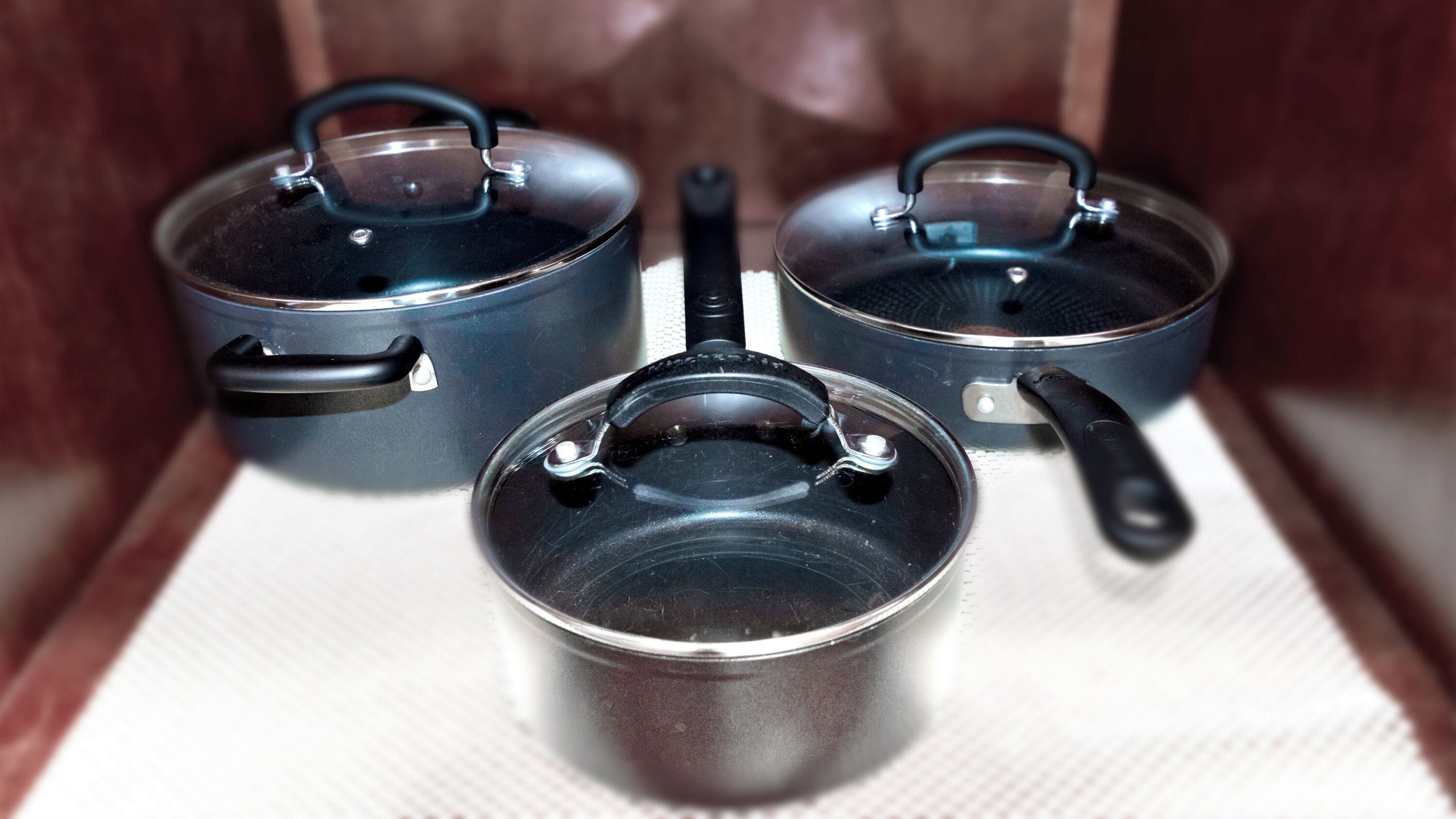 Tres ollas con tapas sobre una encimera de cocina.