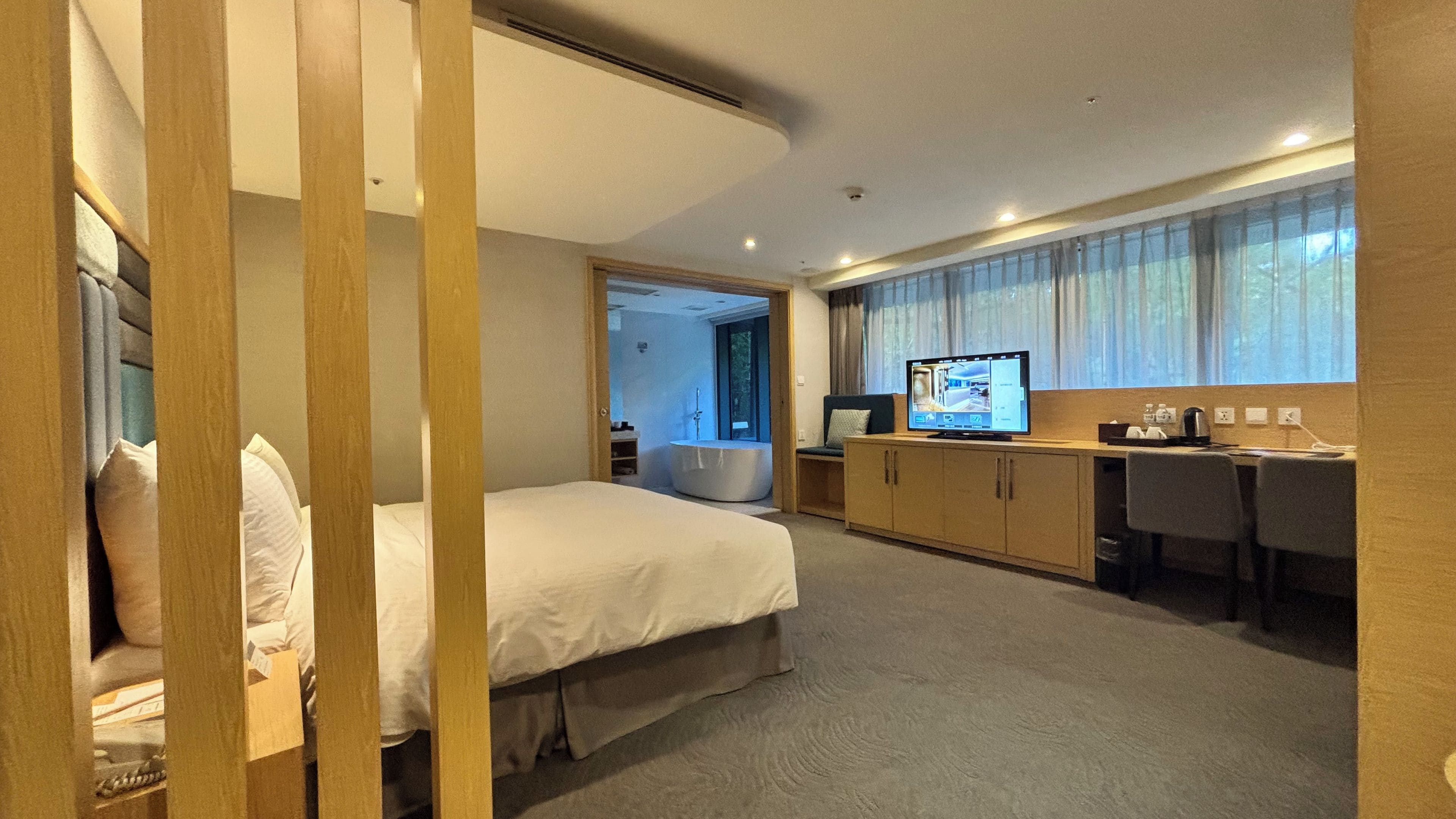 A hotel room with a bed, a desk, a television, and a bathroom.