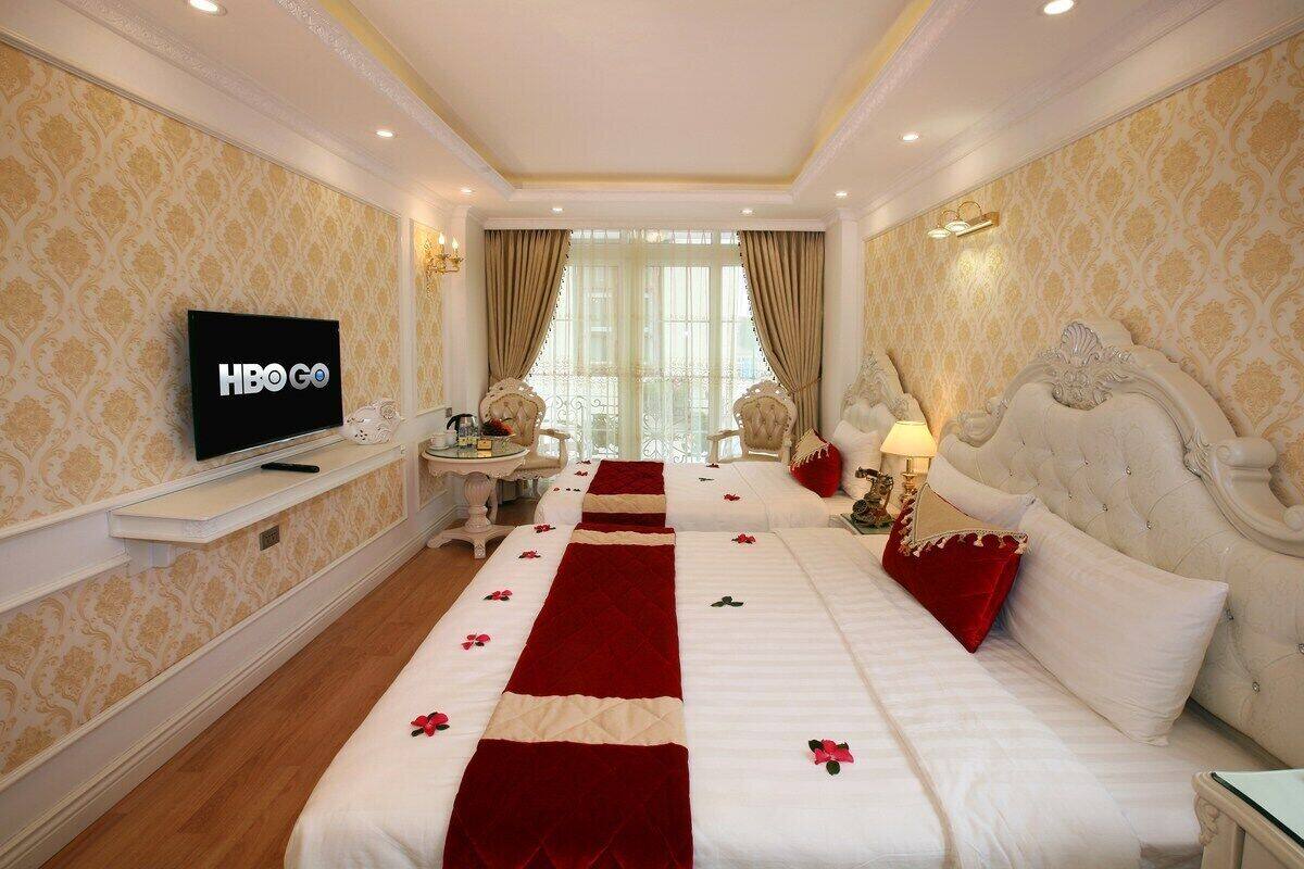 A hotel room with a large bed, a TV, a desk, and a view of the outdoors.