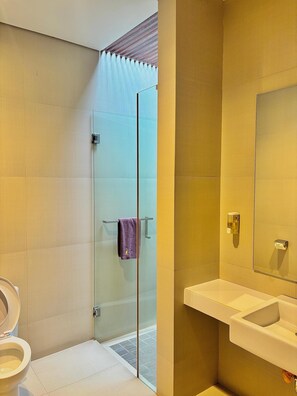 A modern bathroom with a glass shower enclosure, a white sink, and a mirror. - COZY Boutique Guest House (Malang)