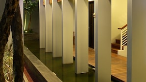Edifici modern amb llistons verticals de fusta i aplics de paret il·luminats, un camí de formigó i una escala.