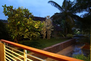 A garden with a palm tree, a cactus, and a water feature. - COZY Boutique Guest House (Malang)