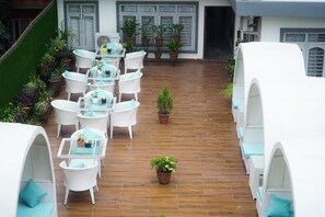 A rooftop patio with white wicker furniture, potted plants, and a small tree. - Hotel Mustang Holiday Inn (Kathmandu)