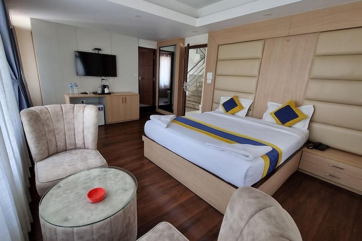 Habitación de hotel con cama, escritorio, silla, televisor y puerta que da a una escalera.