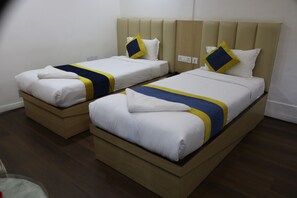 Two single beds with headboards, wooden footboards, and white bedding with blue and yellow accents. - Hotel Mustang Holiday Inn (Kathmandu)