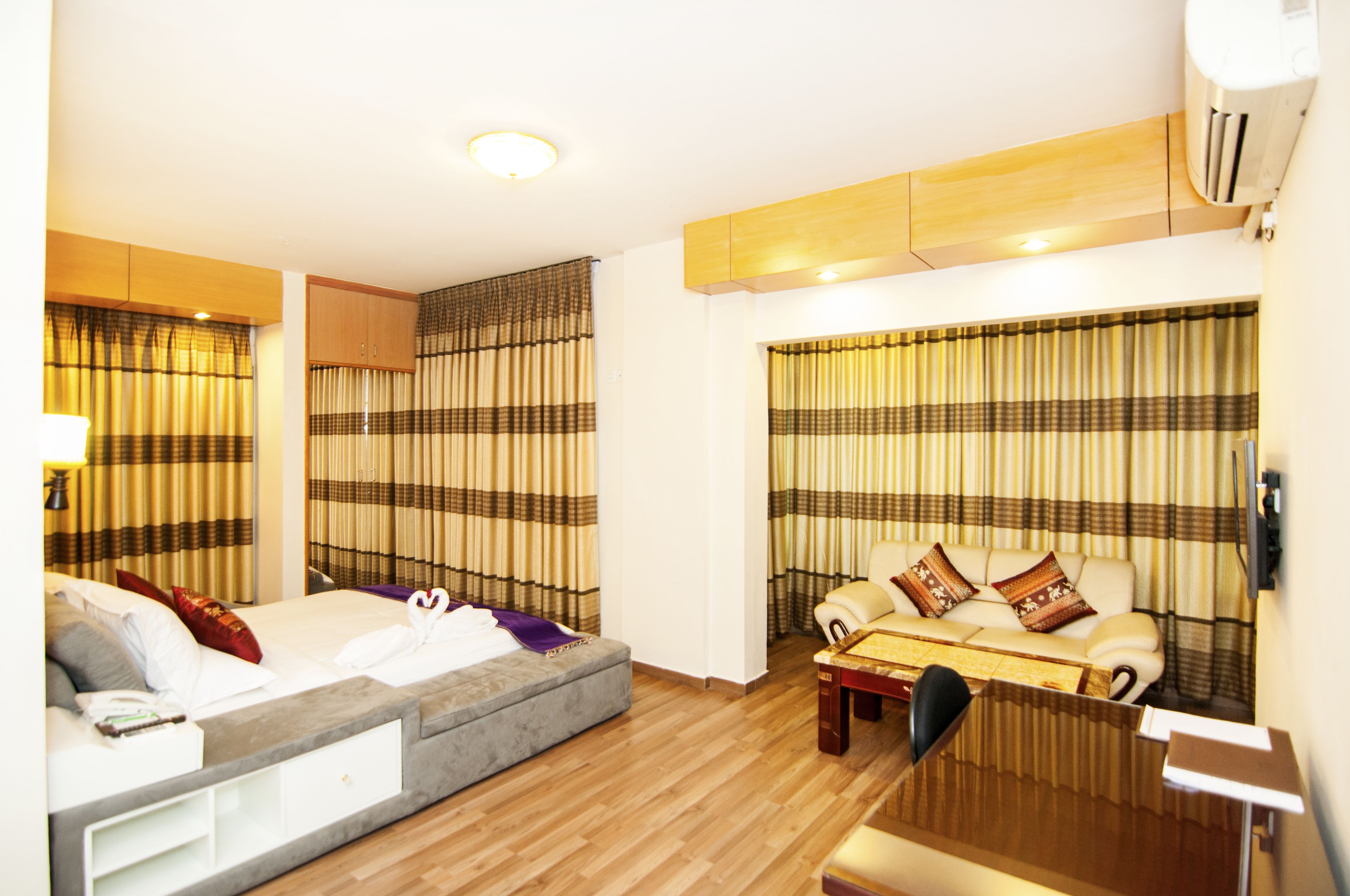 Una habitación de hotel con cama, sofá, mesa de centro y cortinas.