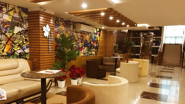 A modern lobby with a sofa, armchairs, a coffee table, and a large plant. - Century Park Residence (Dhaka)
