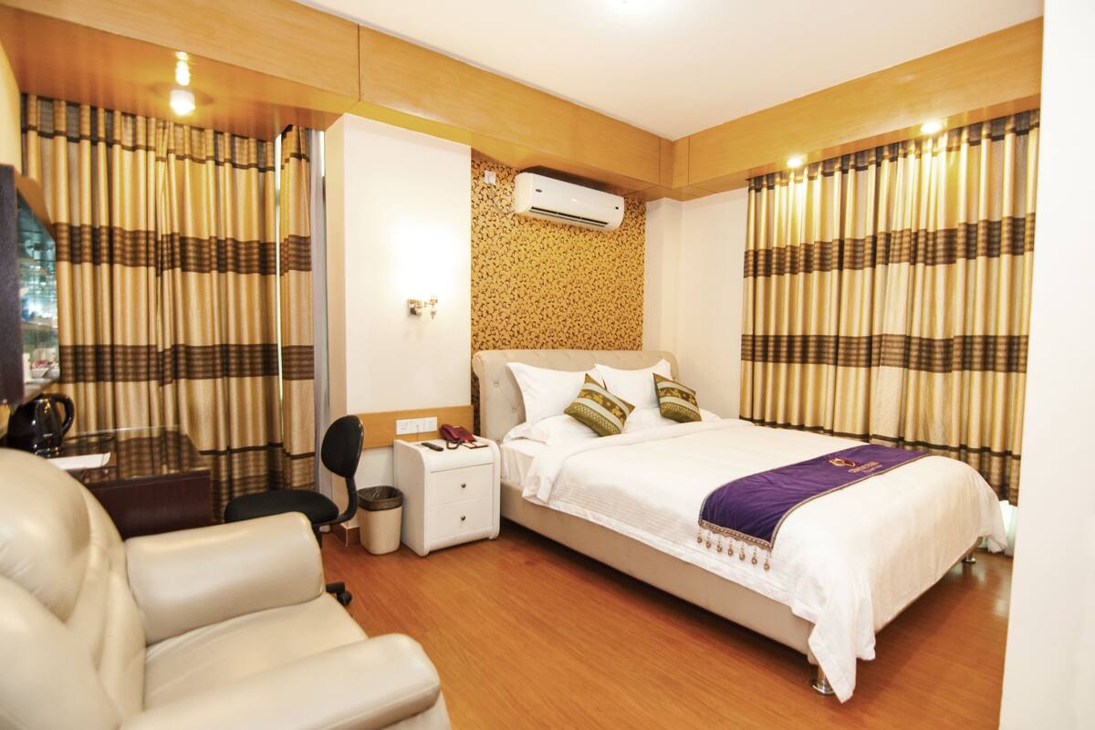 Una habitación de hotel con una cama, un escritorio, una silla y una mesita.