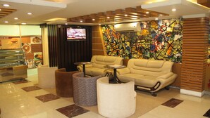 A modern lounge area with leather sofas, a television, and a colorful abstract mural. - Century Park Residence (Dhaka)