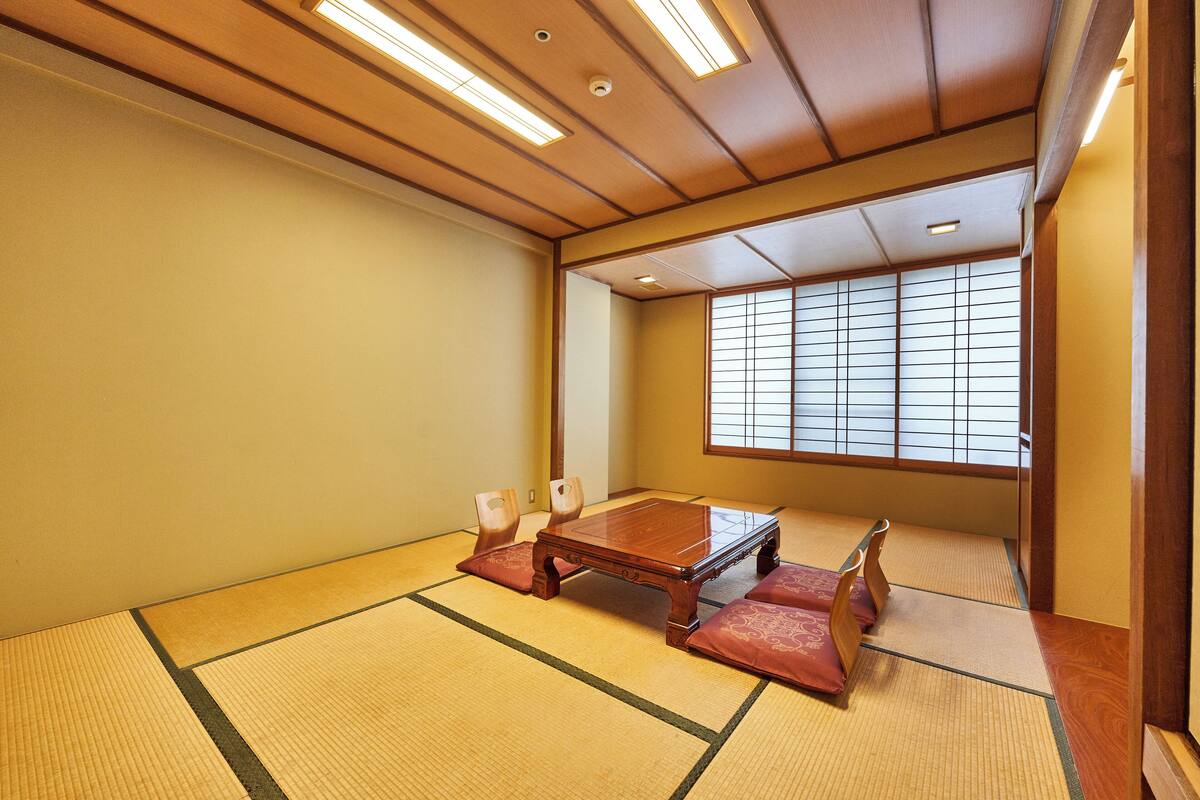 Una habitación japonesa tradicional con suelo de tatami, una mesa de madera baja y puertas correderas shoji.