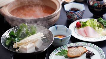 A table with various dishes including a bowl of soup, a plate with sashimi, and a bowl of tofu.