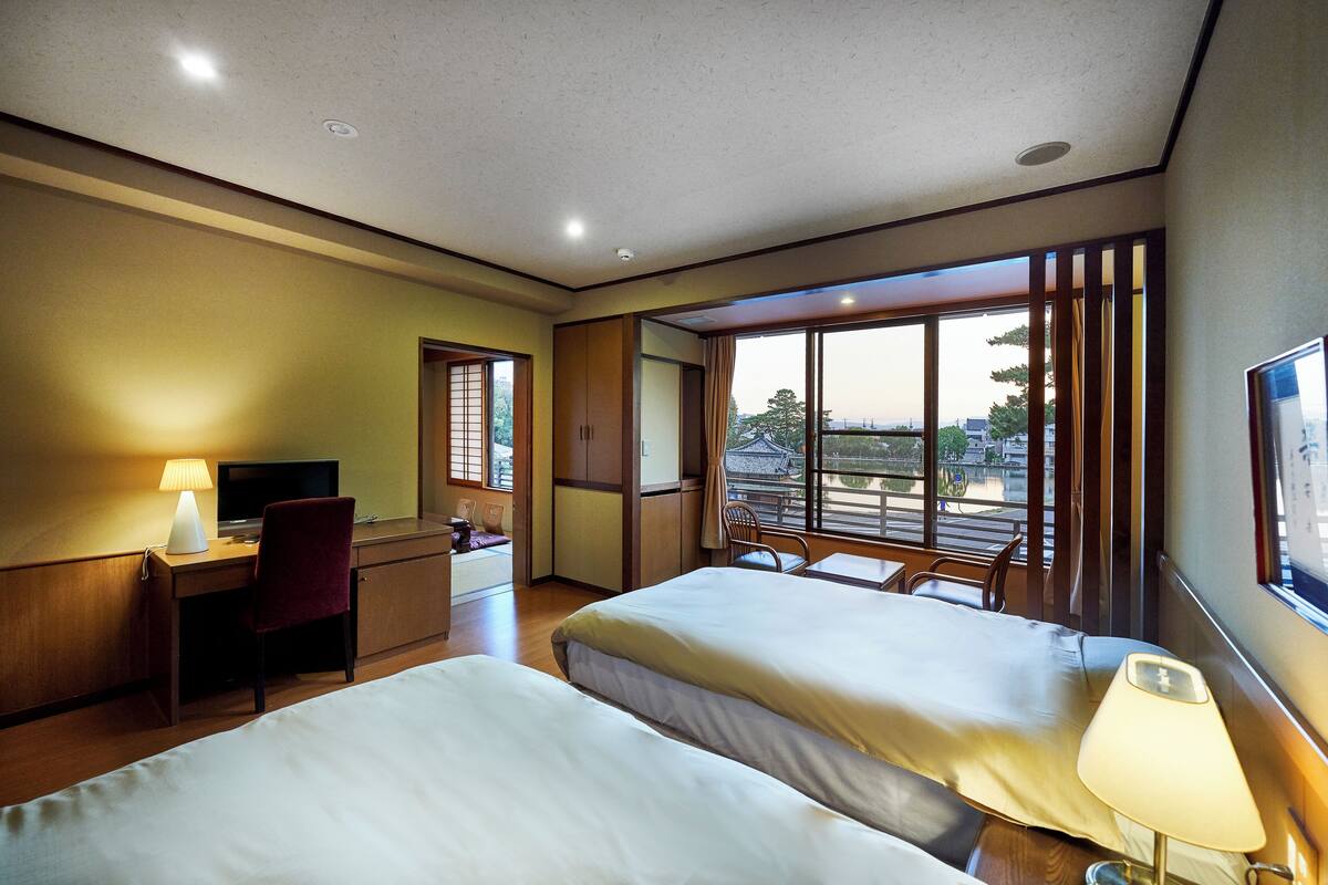 Una habitación de hotel con dos camas, un escritorio, una silla y un televisor.