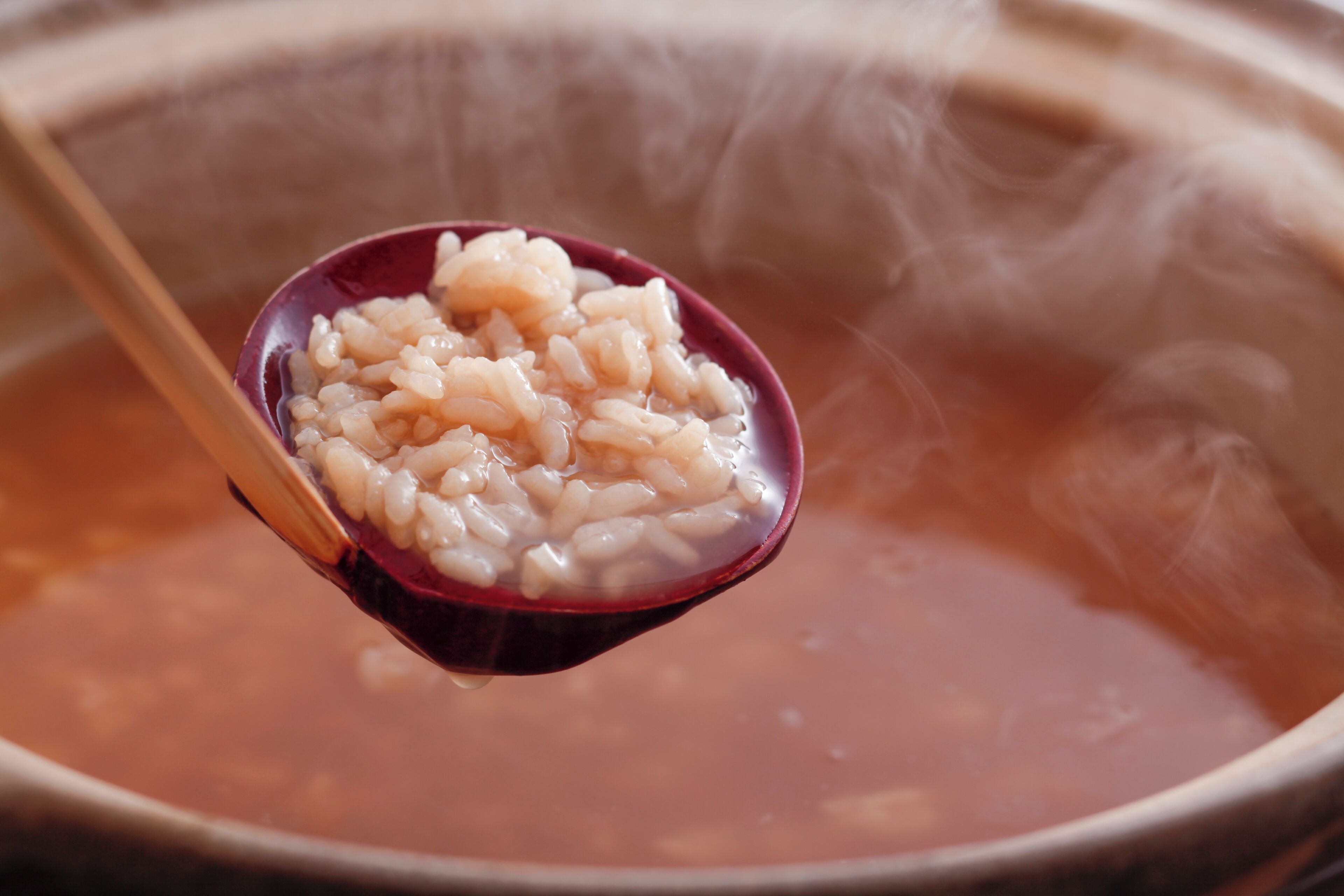 A bowl of rice with a spoonful being lifted, steam rising from the bowl.