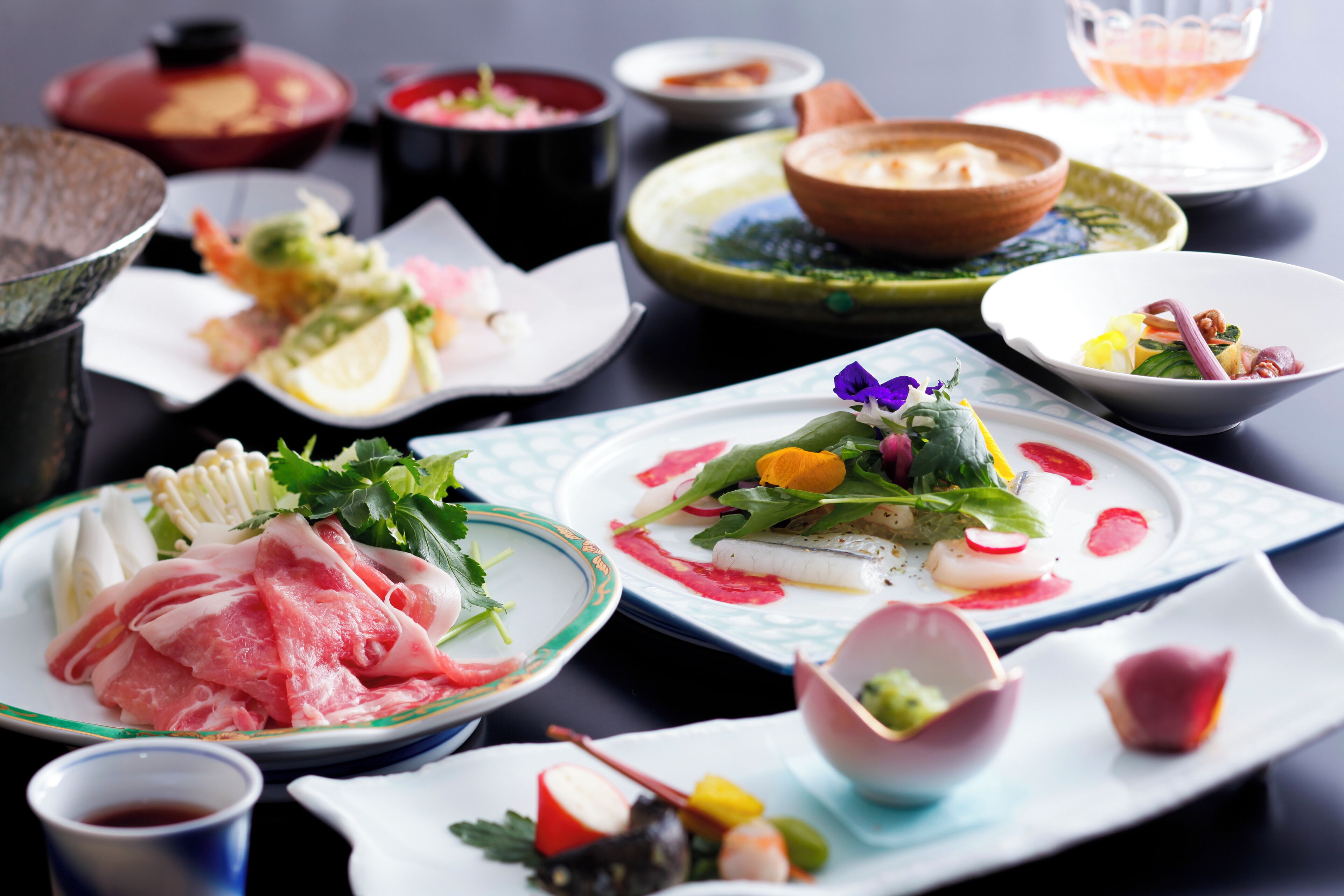 A variety of dishes on a table, including sashimi, vegetables, and a small bowl of soup.