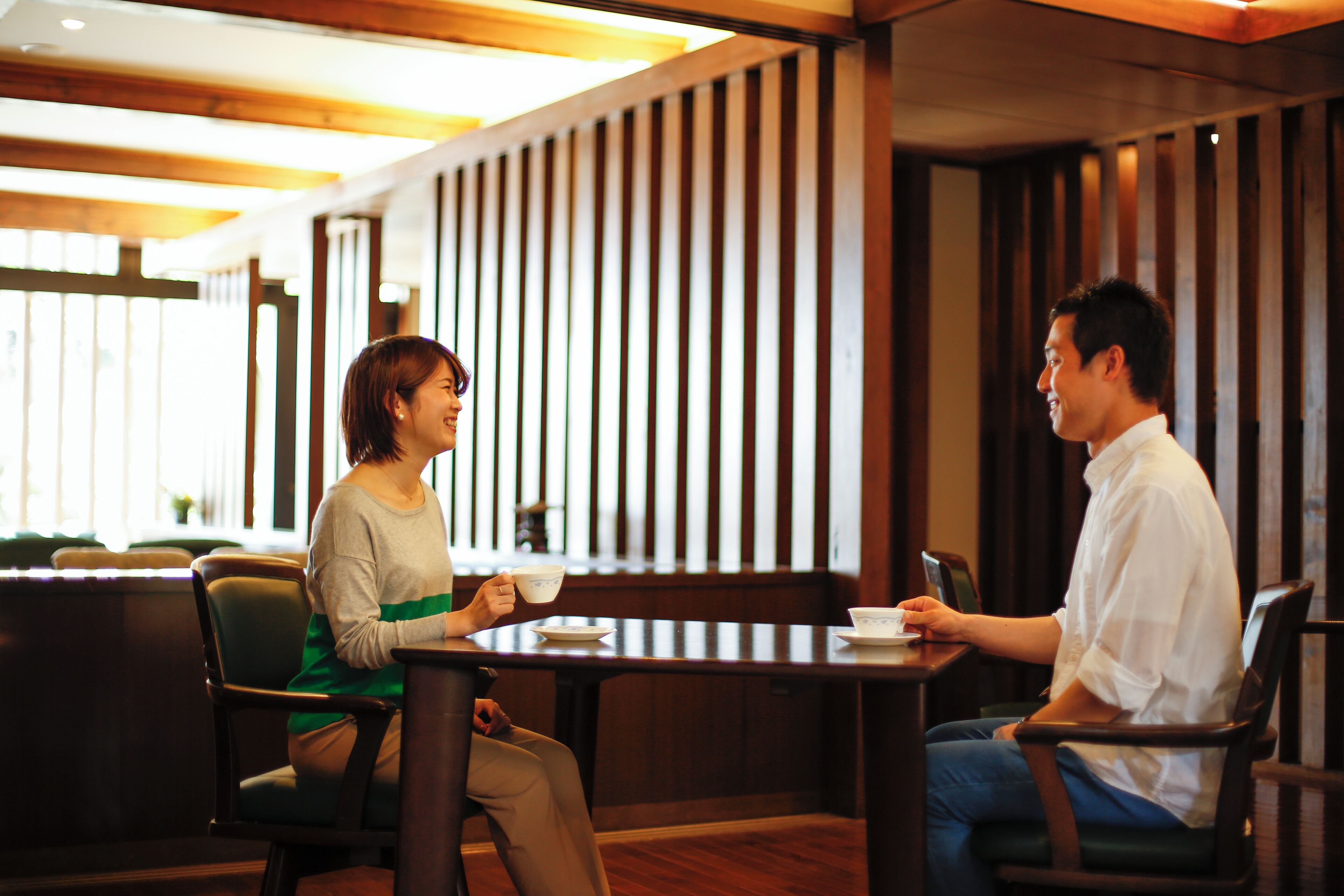 A couple seated at a table in a restaurant with wooden paneling and a view of the outdoors.
