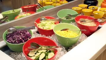 A buffet with various food items in colorful bowls on ice.
