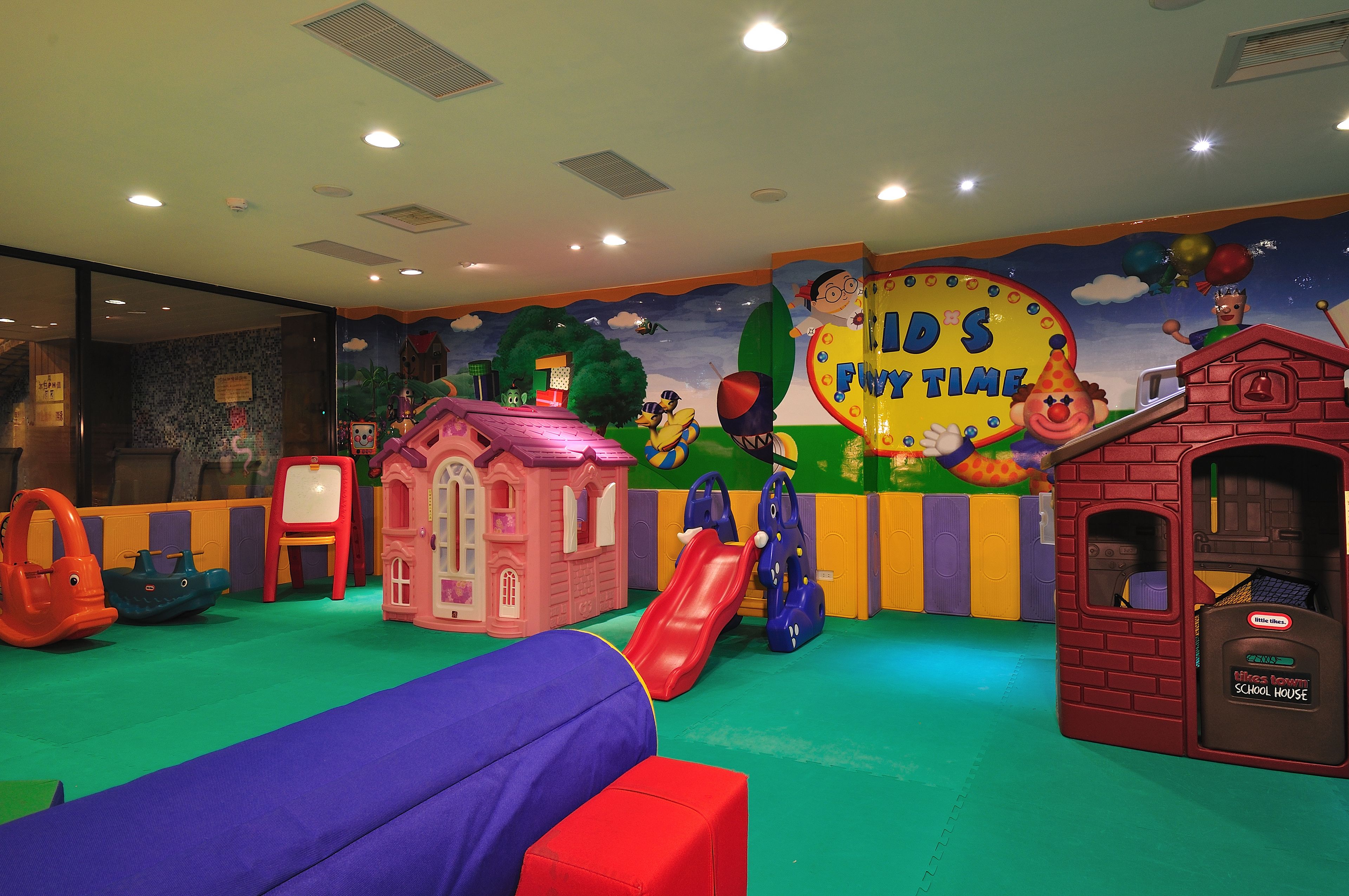 A children's play area with slides, a small pink house, and a red playhouse.