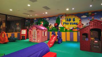 A children's play area with slides, a small pink house, and a red playhouse.