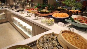 A buffet with various dishes, including a large woven basket of food, a blue plate with a dish, and several bowls of different foods. - Hoya Hot Springs Resort & Spa (Taimali)