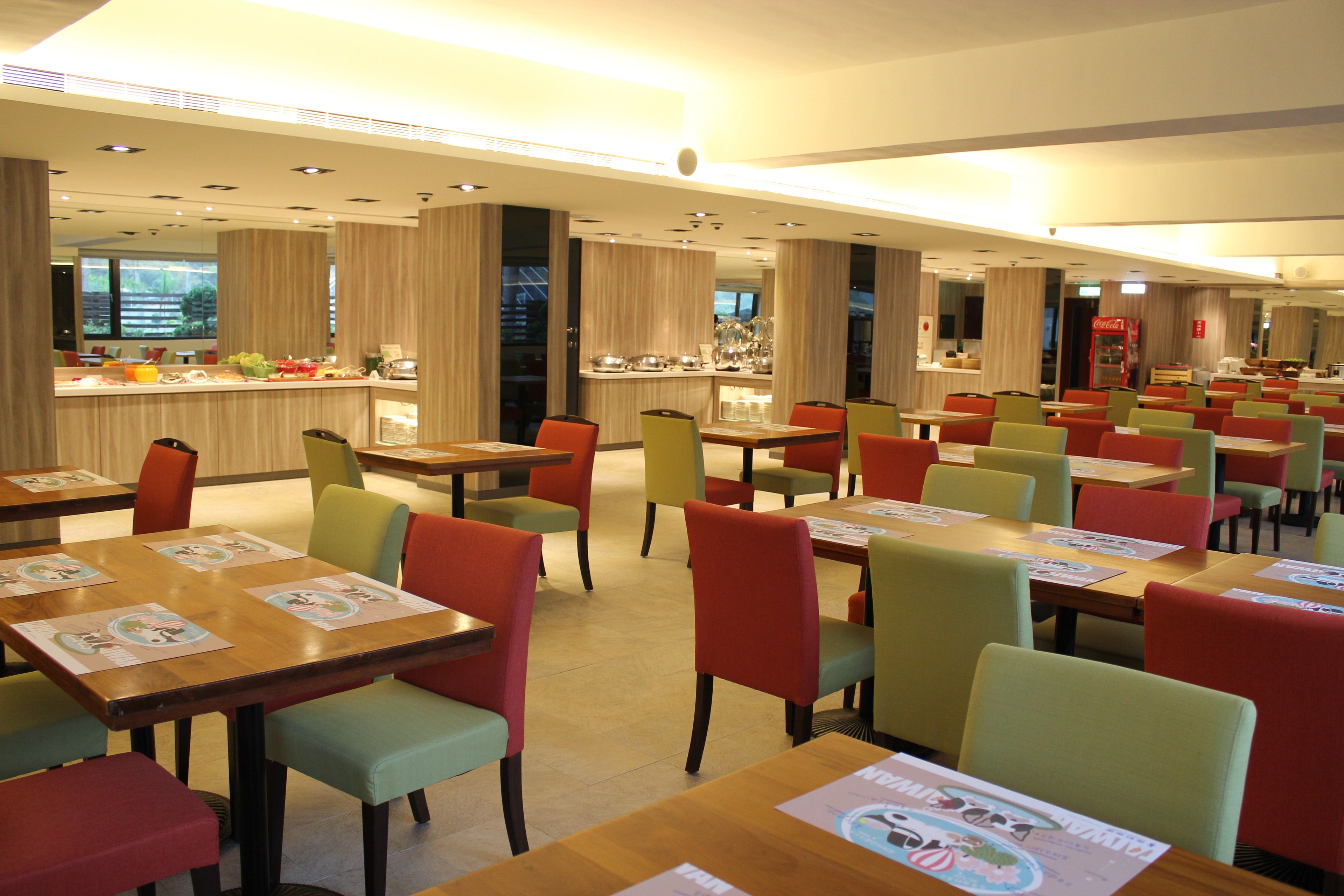 A modern restaurant with multiple tables and chairs, a bar area, and a view of the outdoors.
