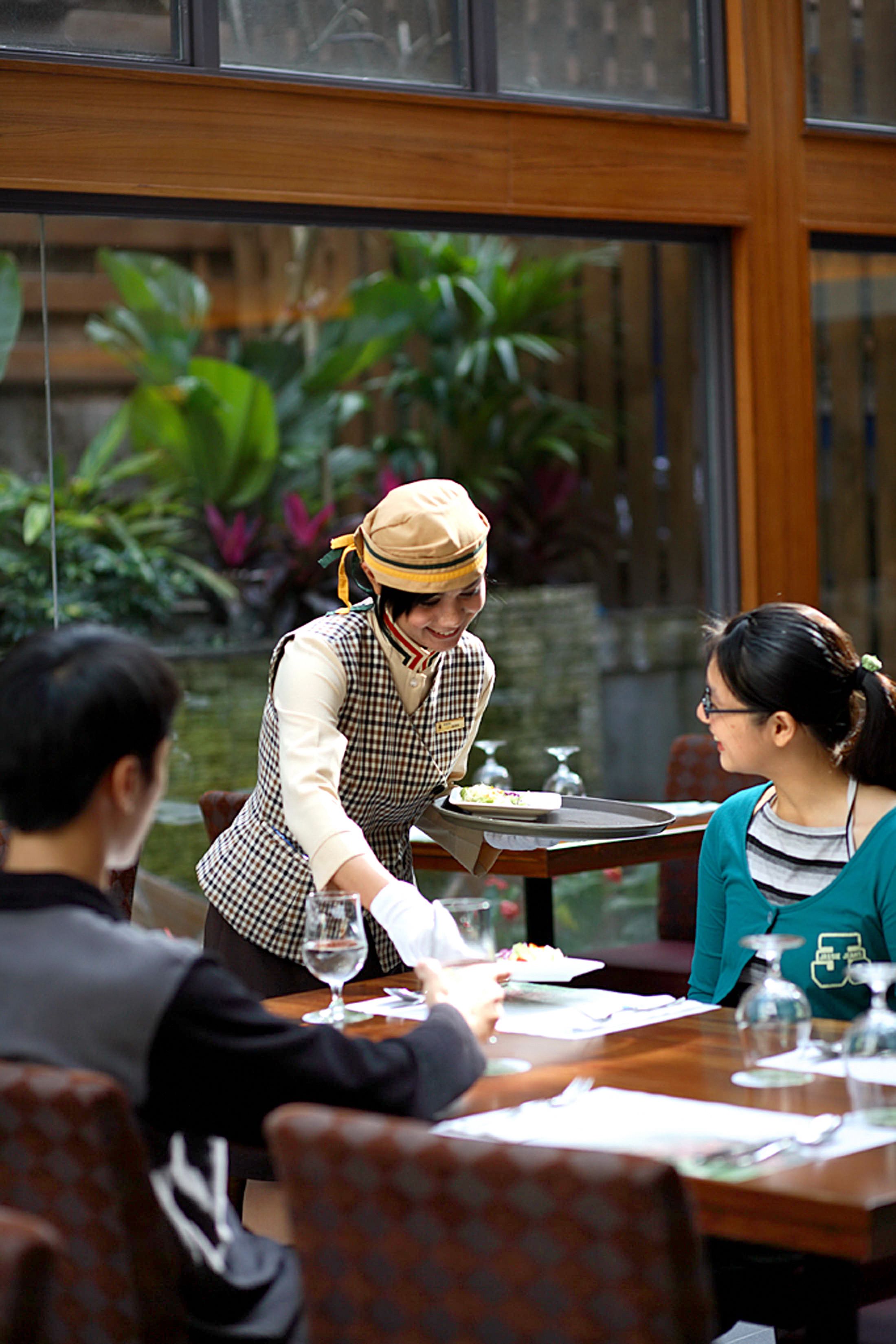 A restaurant setting with a waiter serving a meal to a table.
