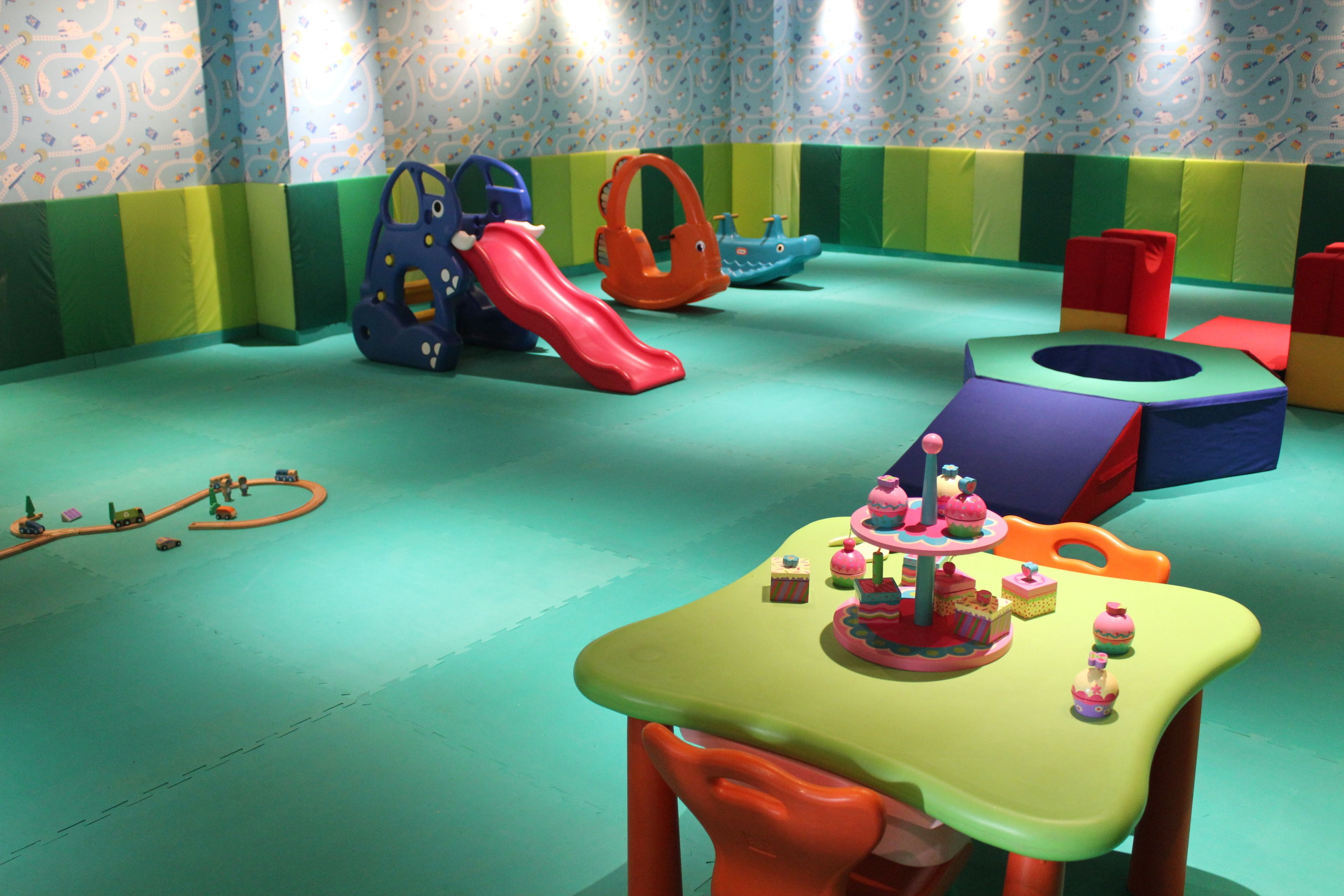 Zona de juegos con estructuras coloridas y una mesa con pequeños pasteles.
