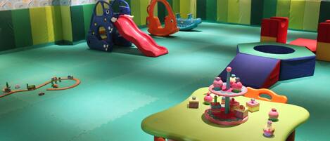 Zona de juegos con estructuras coloridas y una mesa con pequeños pasteles.
