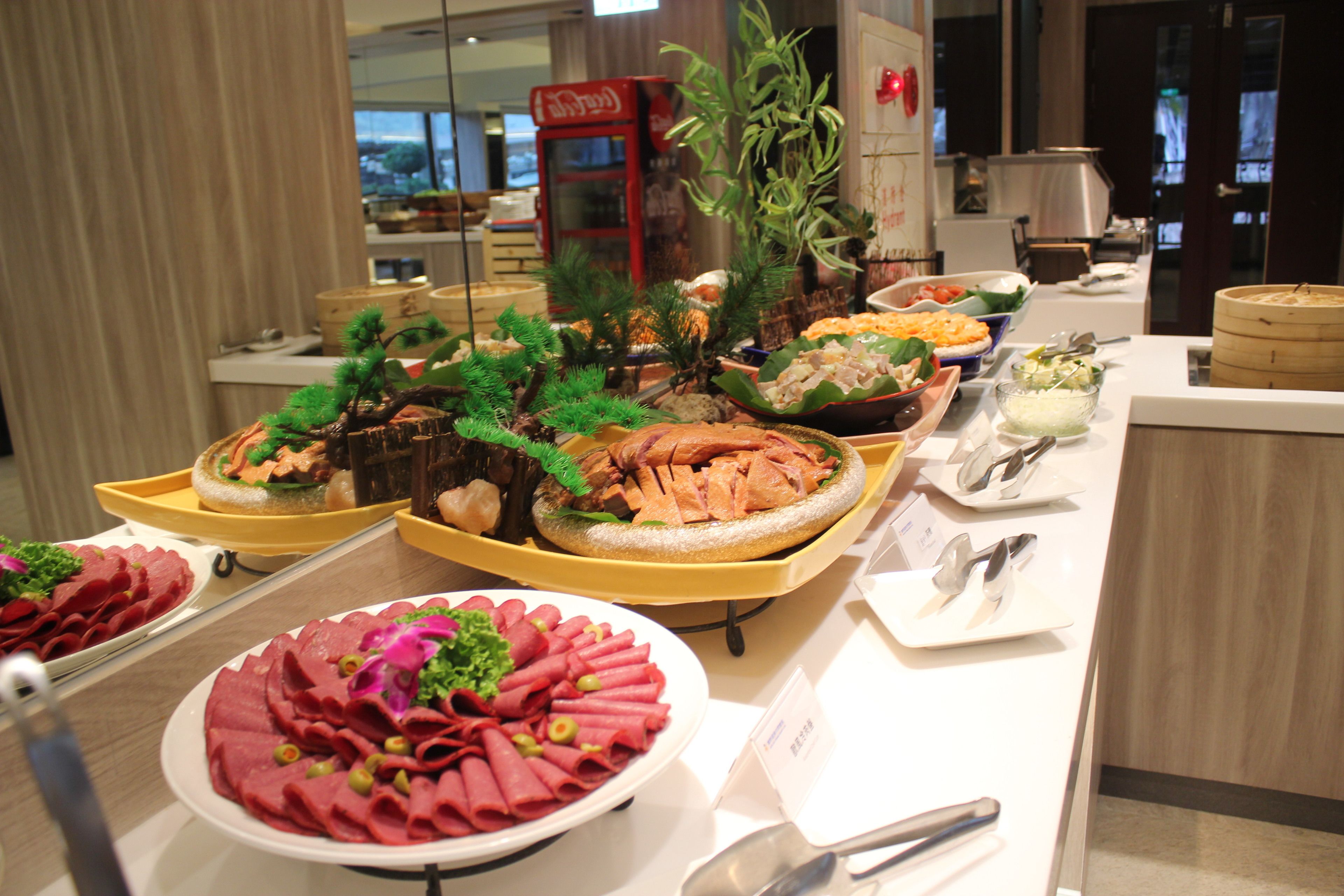 Un buffet proposant une variété de plats, notamment des viandes et des légumes, présentés sur des plateaux jaunes.
