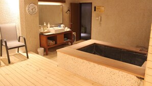 A bathroom with a wooden bathtub, a sink, a mirror, and a chair. - Hoya Hot Springs Resort & Spa (Taimali)
