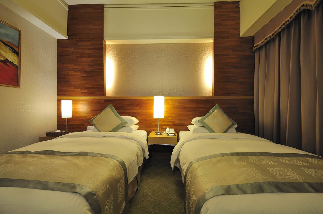 A hotel room with two beds, wooden headboard, nightstands with lamps, and a painting on the wall.