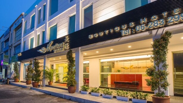 Un hotel con fachada moderna, amplias ventanas y un área de recepción con un mostrador y sillas a la vista.