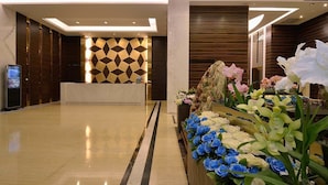 A modern lobby with a reception desk, a digital information kiosk, and a decorative floral arrangement. - Hoya Resort Hotel Taitung (Taitung)