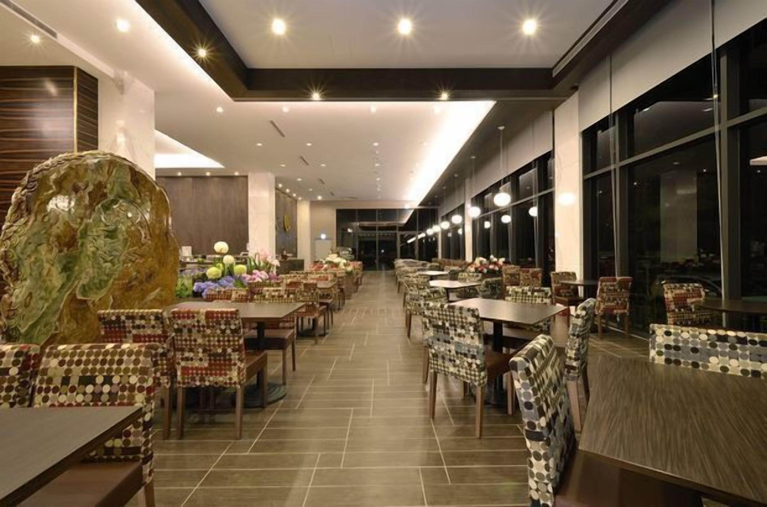 A spacious restaurant with multiple dining tables and chairs, a large decorative rock centerpiece, and a modern interior design.