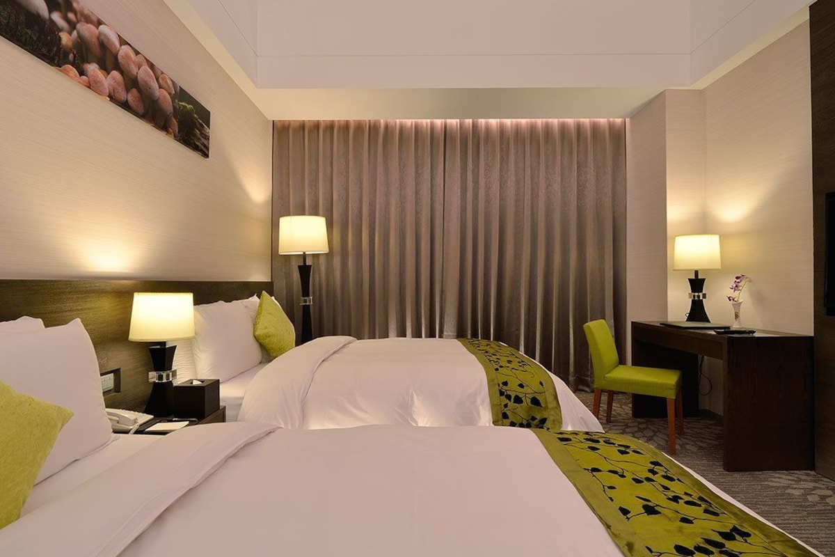 Une chambre d’hôtel avec deux lits, un bureau, une chaise et un téléviseur.