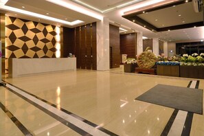 A spacious lobby with a reception desk, a patterned wall, and a decorative centerpiece.