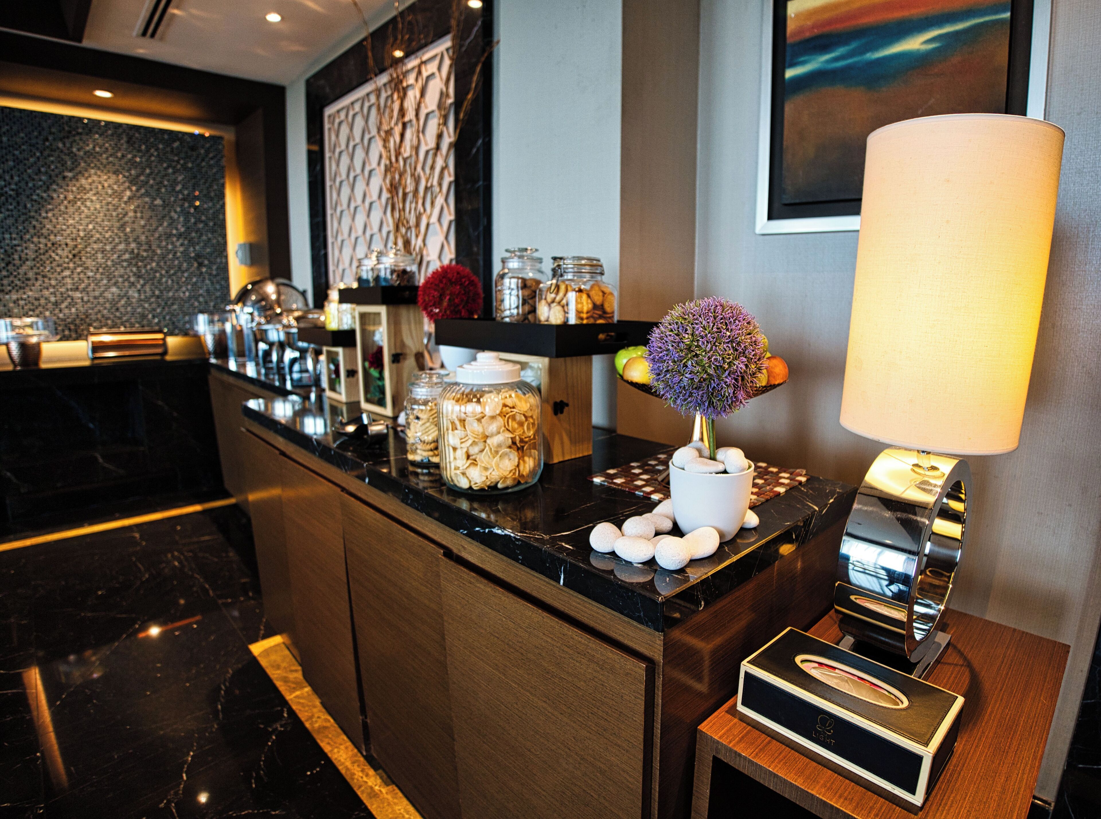 A modern kitchen with marble countertops, a coffee machine, and decorative jars.