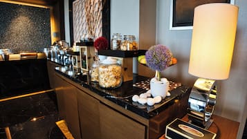 A modern kitchen with marble countertops, a coffee machine, and decorative jars.
