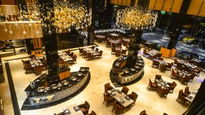 Ein geräumiges Restaurant mit verschiedenen Essbereichen, einer zentralen Bar und großen Kronleuchtern.