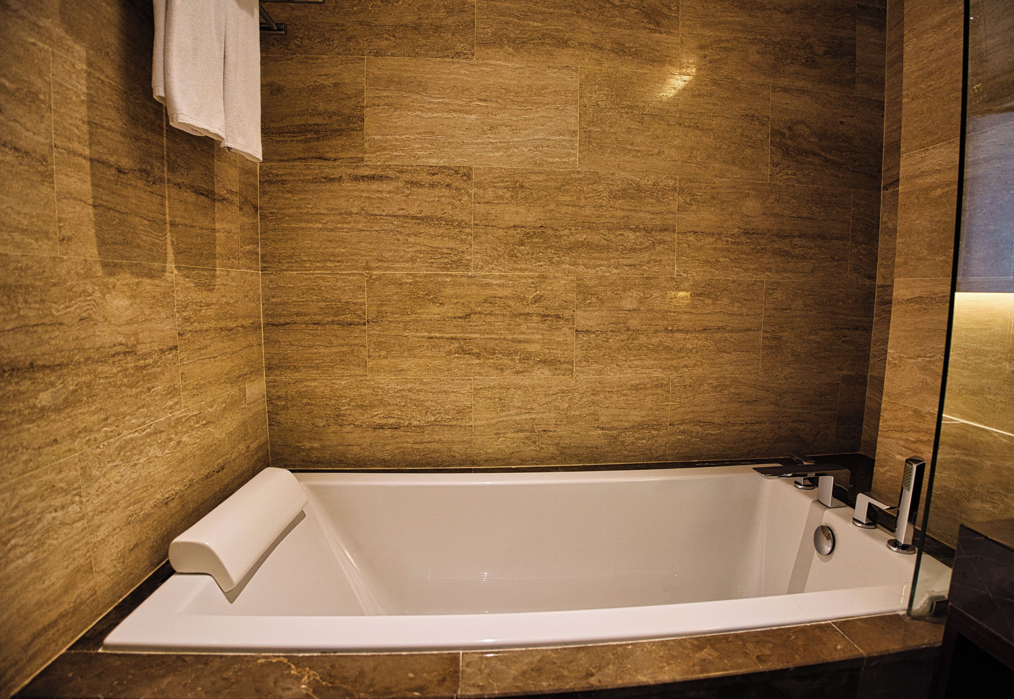 Un baño moderno con una bañera grande, paredes de mármol y una cabina de ducha de vidrio.