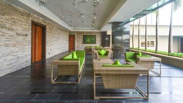 A modern lobby with wicker furniture, a large painting, and a view of palm trees.