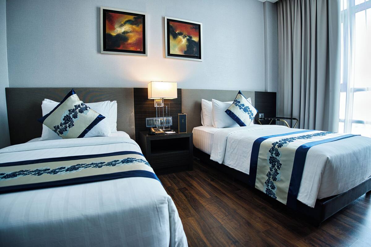 Une chambre d’hôtel avec deux lits, une table de chevet avec une lampe et des œuvres d’art accrochées au mur.