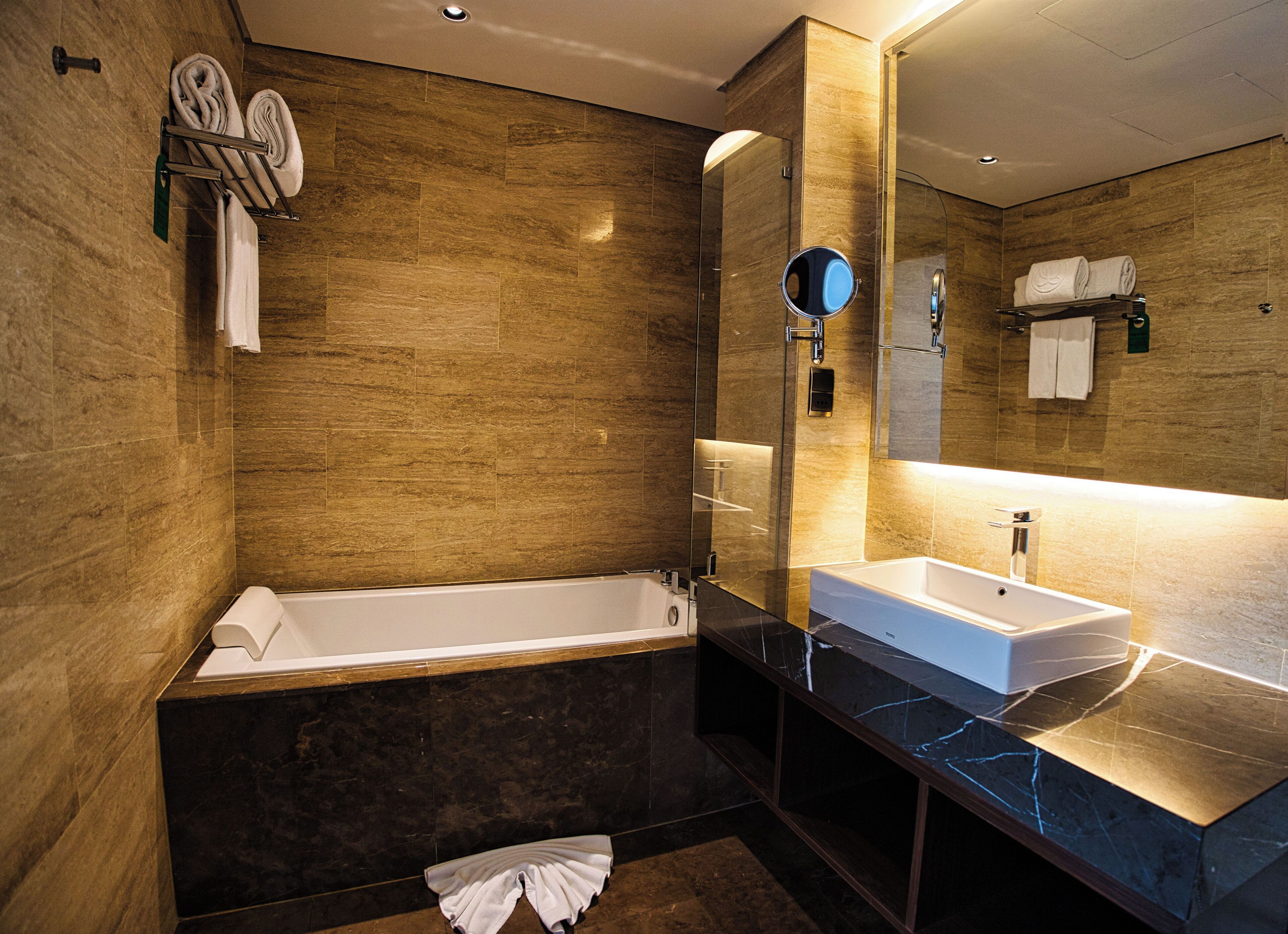 Ein modernes Badezimmer mit einer Badewanne, einem Waschbecken und einem großen Spiegel.