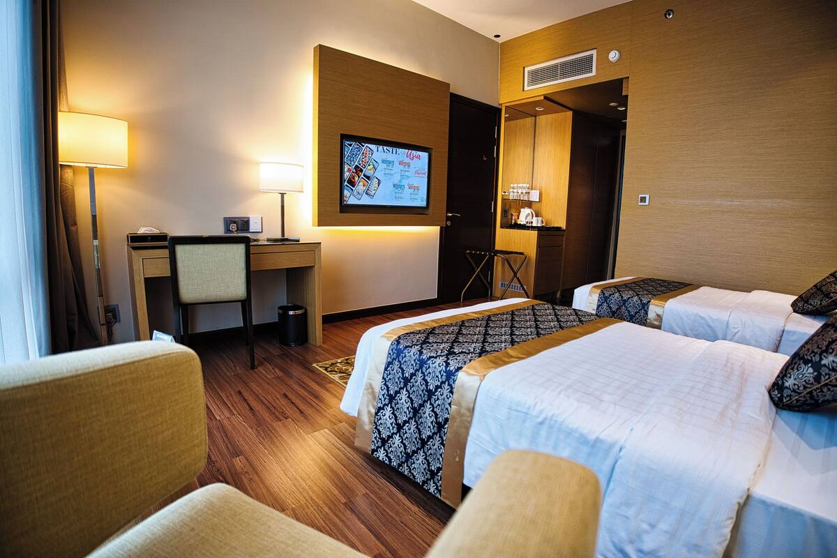 Une chambre d’hôtel avec deux lits, un bureau, une chaise, une télévision et une lampe.