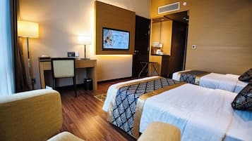 Een hotelkamer met twee bedden, een bureau, een stoel, een televisie en een lamp.