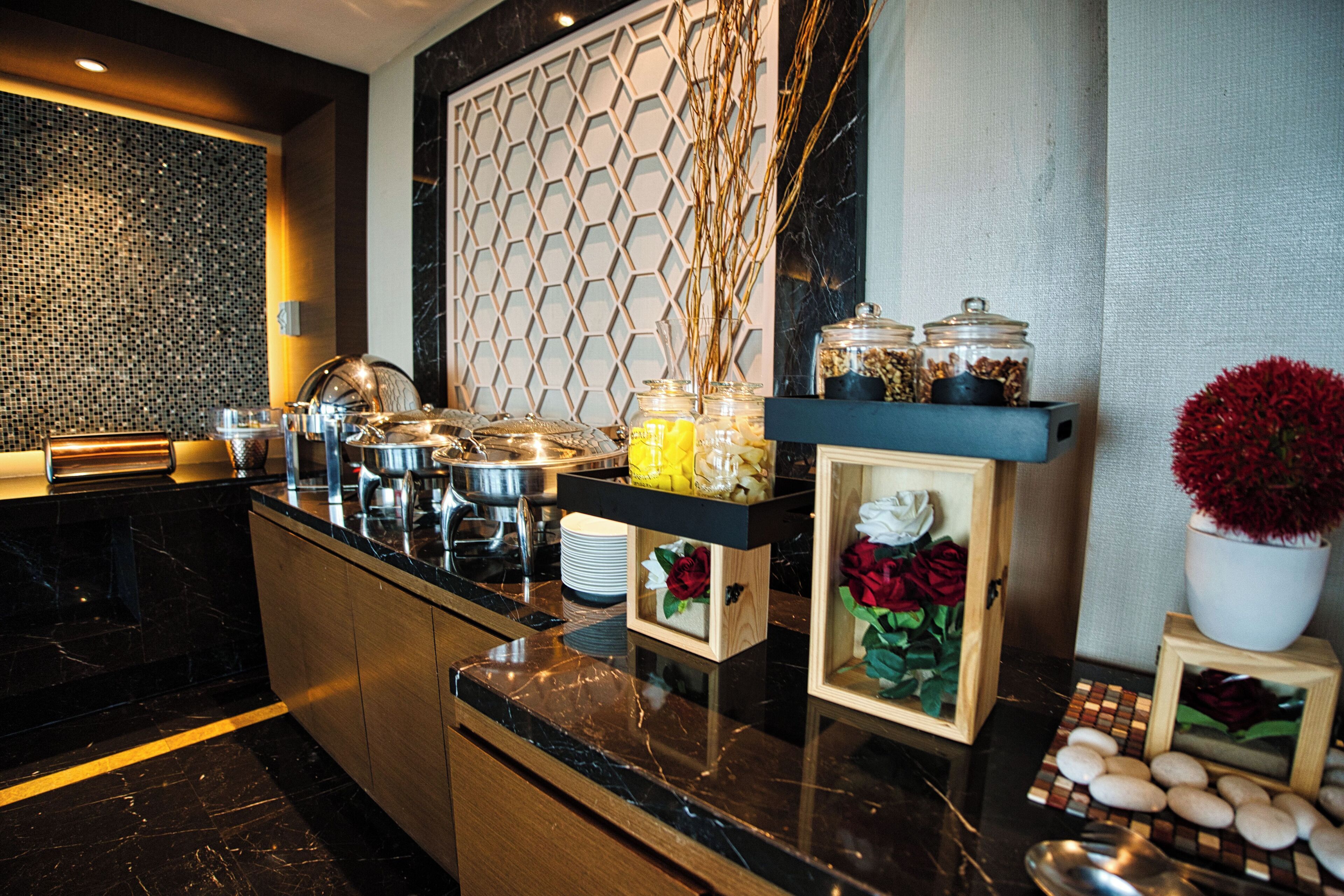 A modern kitchen with a marble countertop, a hexagonal patterned wall, and various food items and decorations.